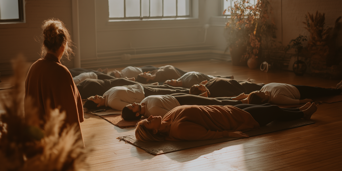 משתתפים שוכבים בתרגול ריברסינג קבוצתי, בליווי מנחה, באווירה רגועה ובאור רך.